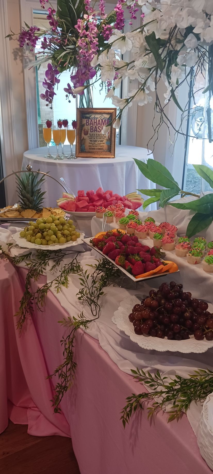 A table with plates of fruit and flowers on it.