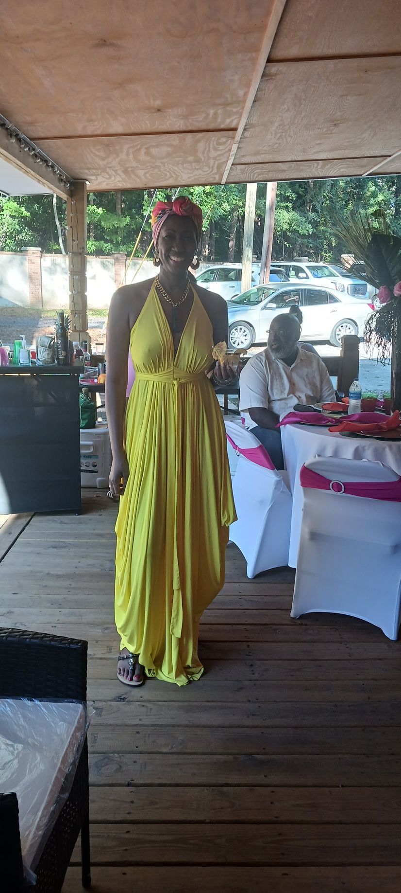 A woman in a yellow dress is standing in a room with tables and chairs.