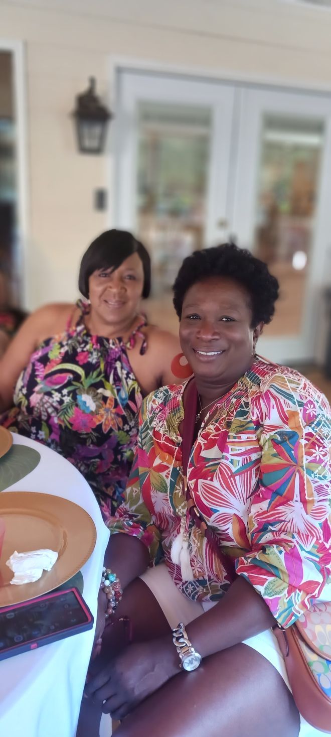 Two women are sitting at a table and smiling for the camera.