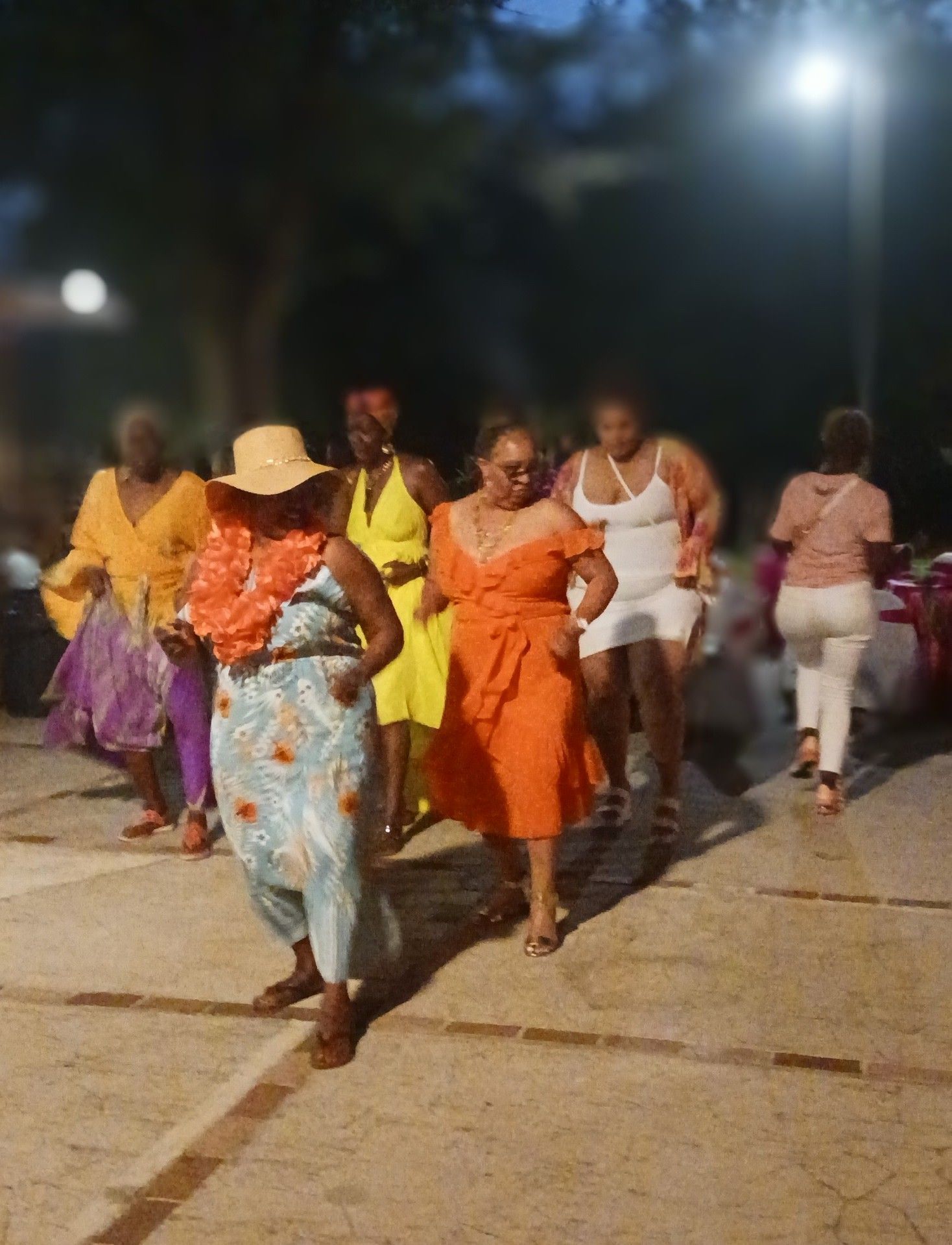 A group of women are dancing in a parking lot at night