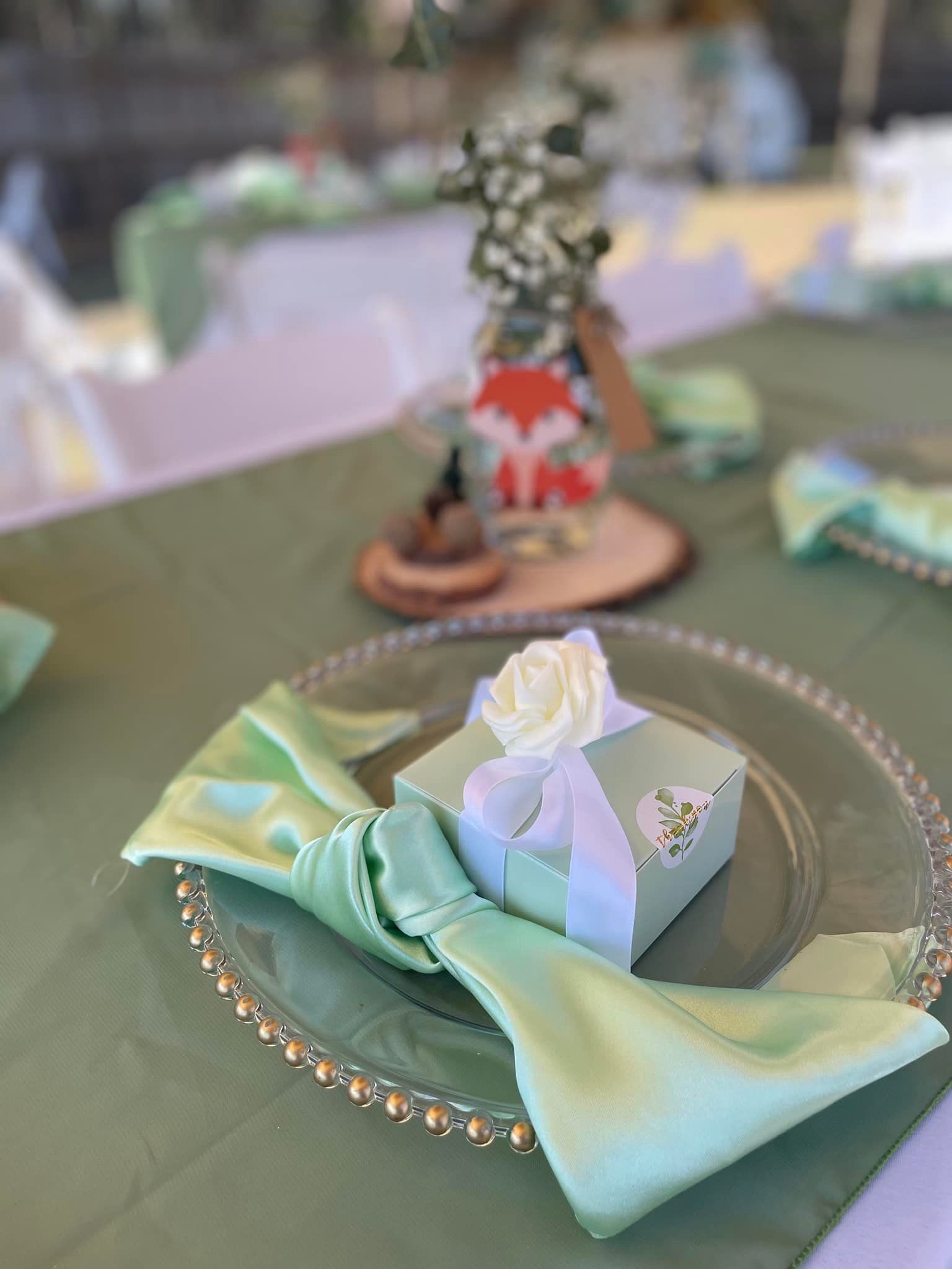 A plate with a napkin and a gift box on it on a table.