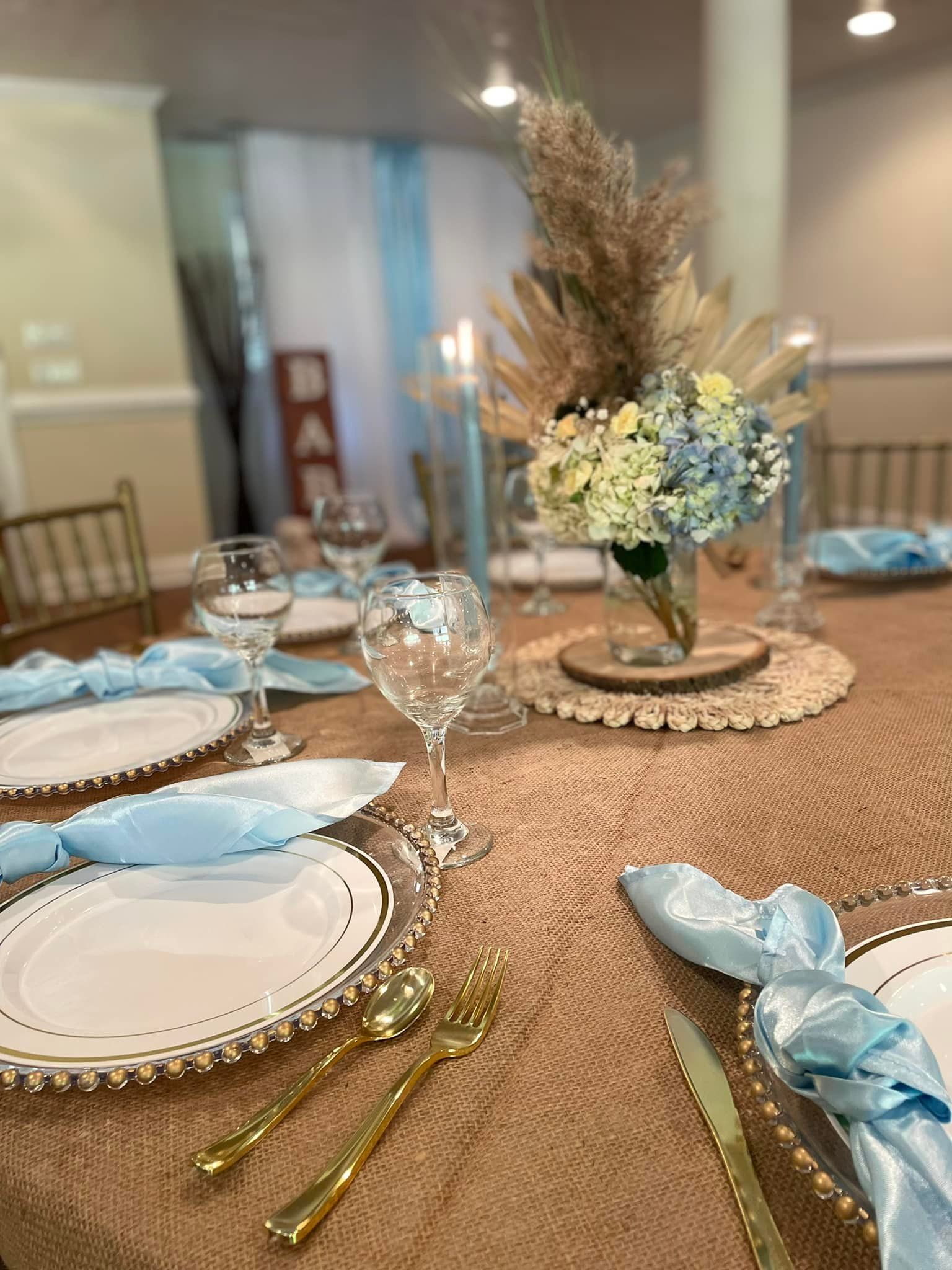 A table with plates , utensils , and a vase of flowers on it.
