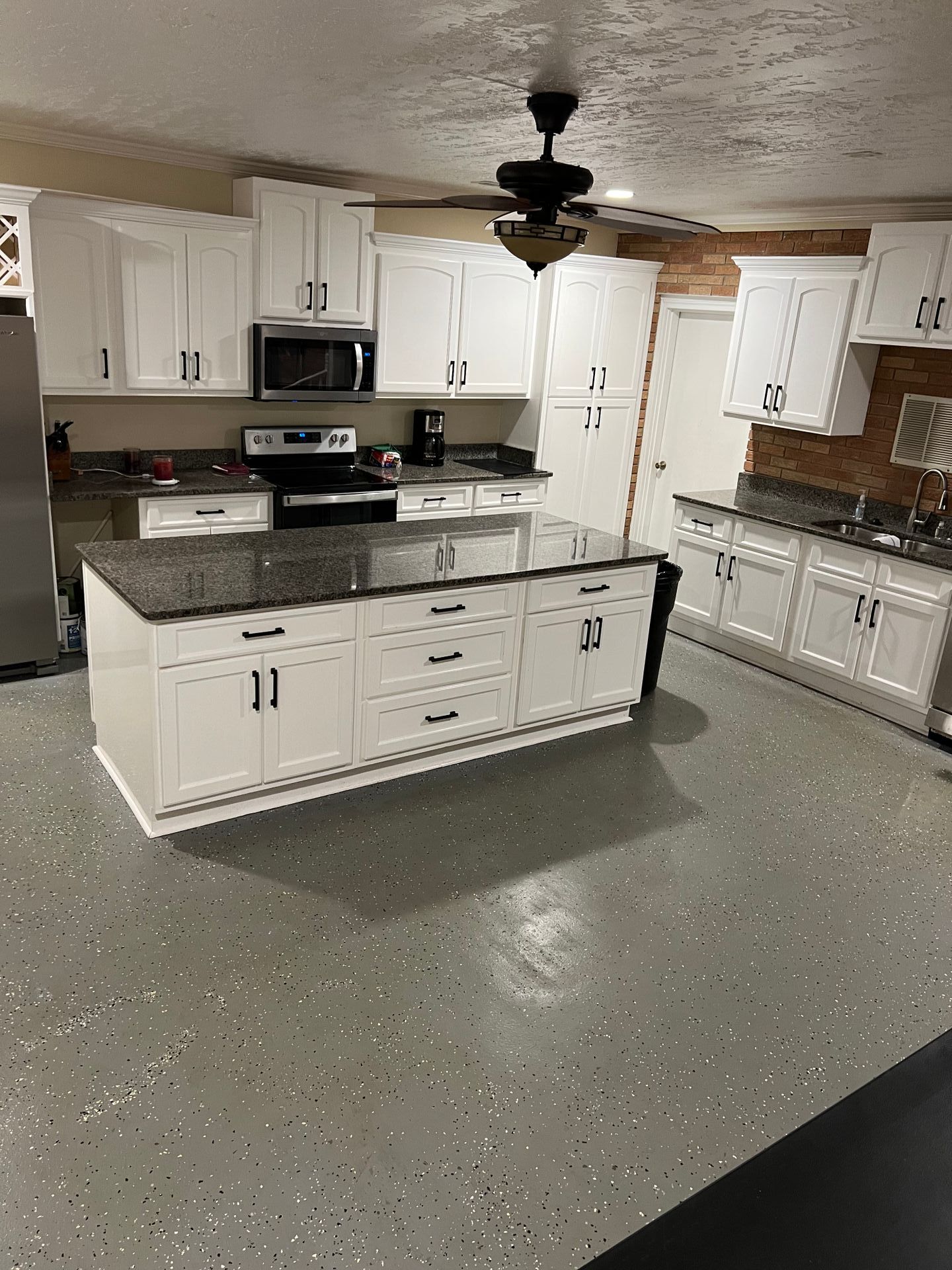 A kitchen with white cabinets , granite counter tops , and a ceiling fan.