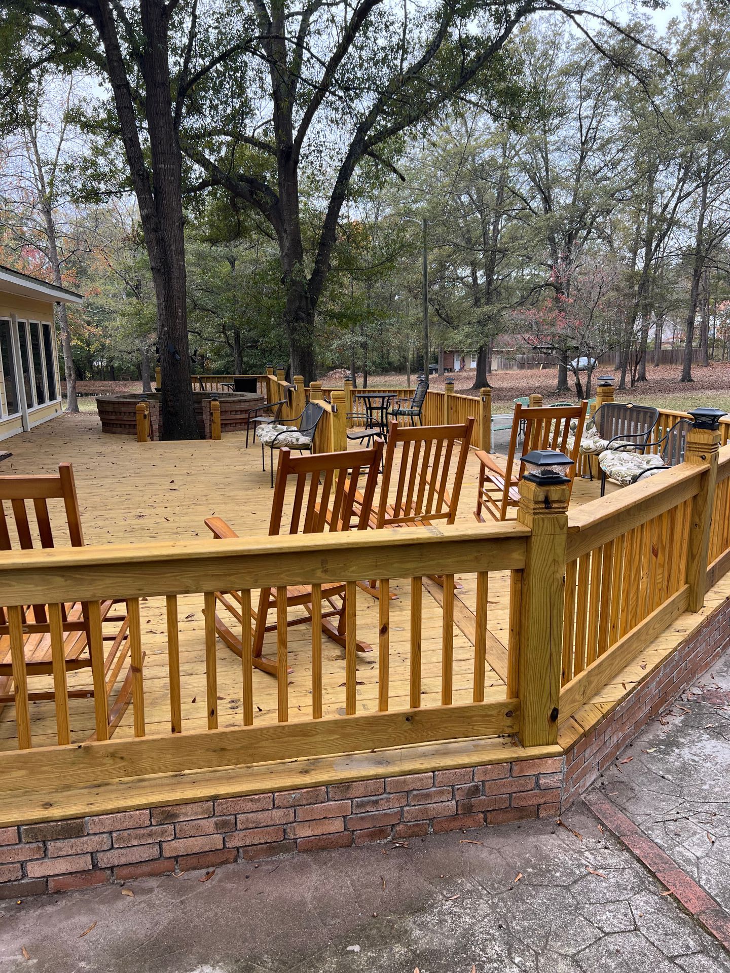 A large wooden deck with a wooden railing and chairs.