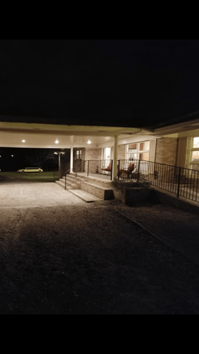 The front porch of a house is lit up at night.