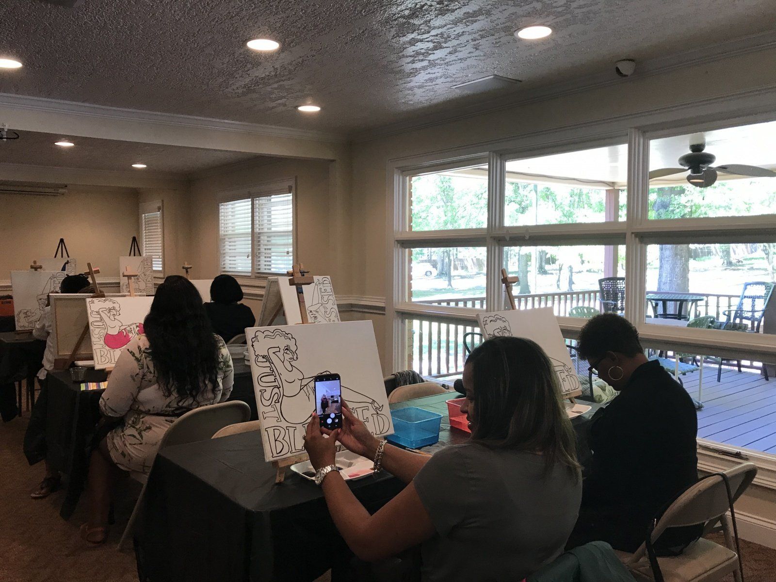 A group of people are sitting at a table painting.