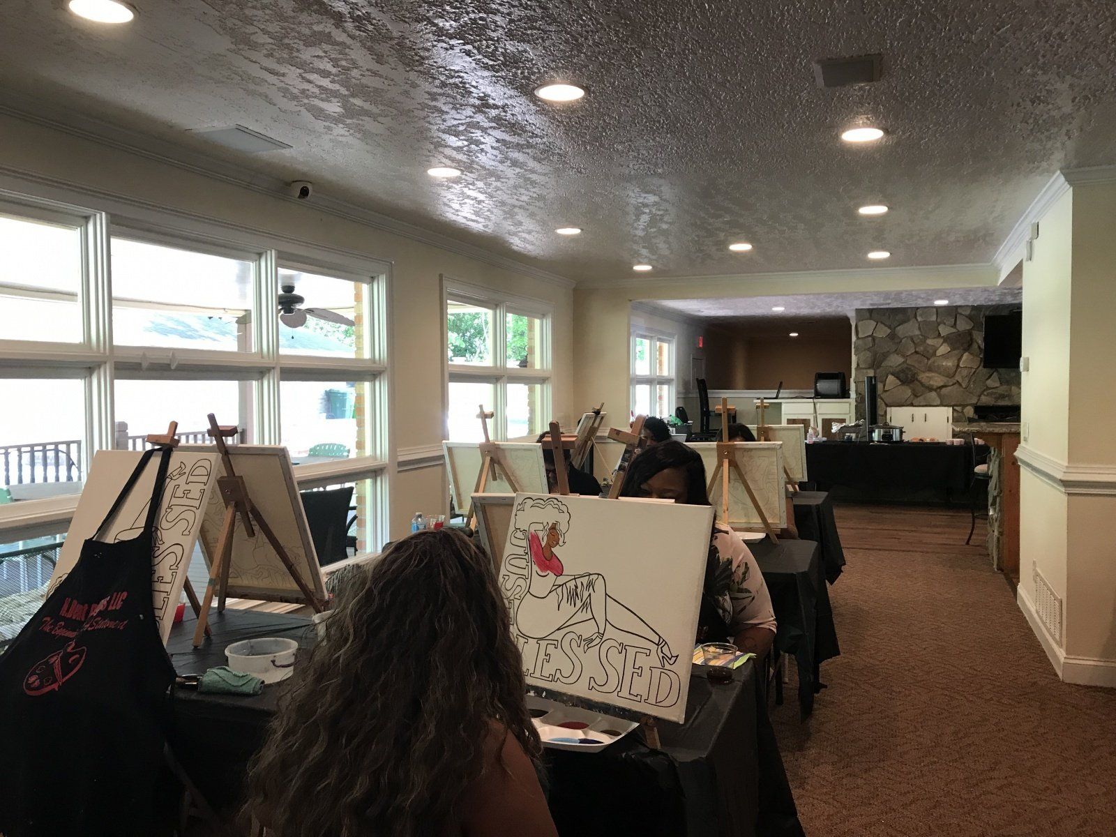 A group of people are painting on canvases in a room.