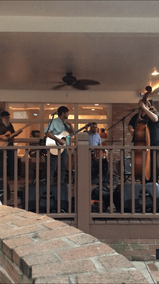 A group of people are playing instruments on a porch.