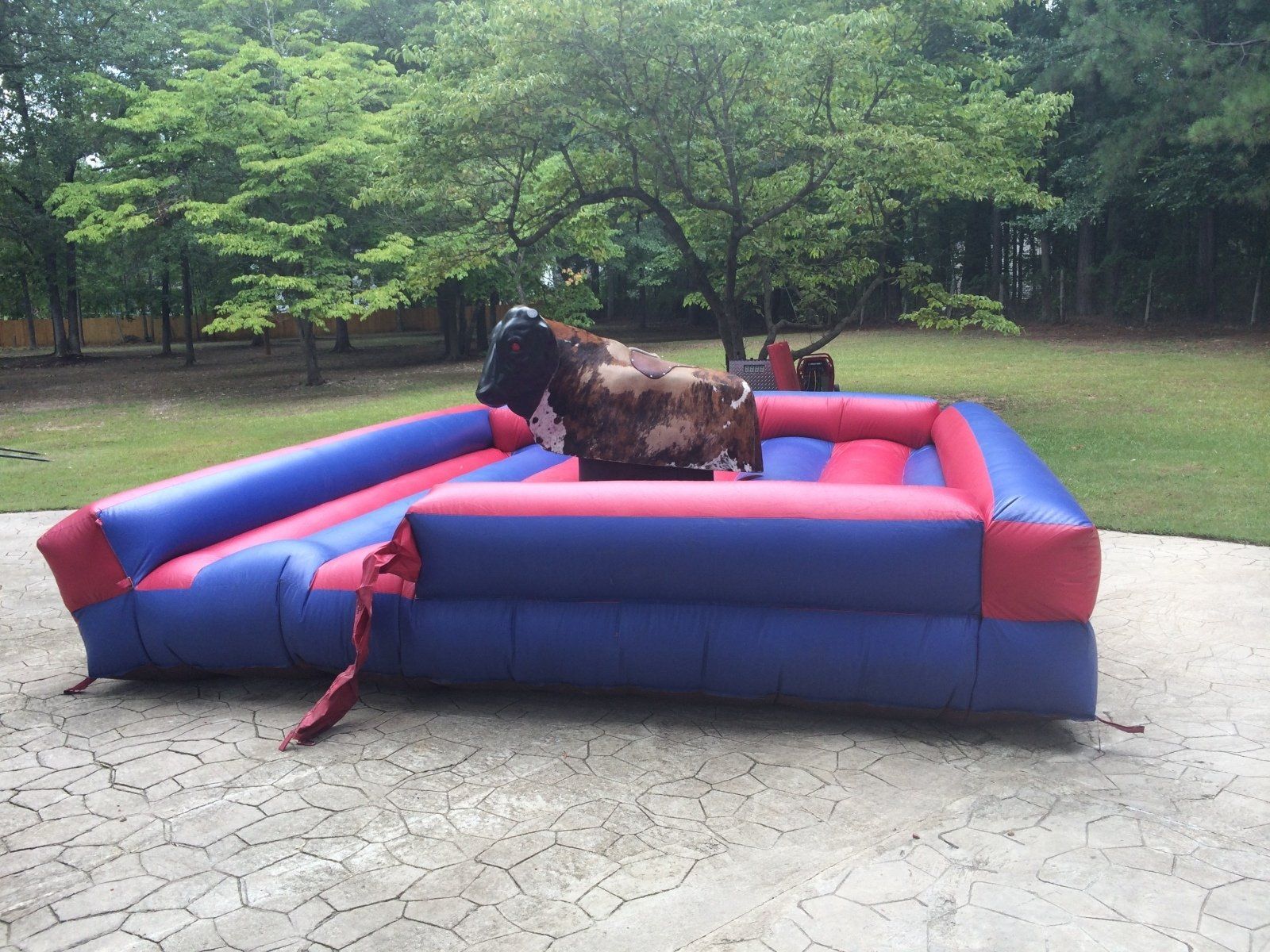 A man is riding a bull on a red and blue inflatable