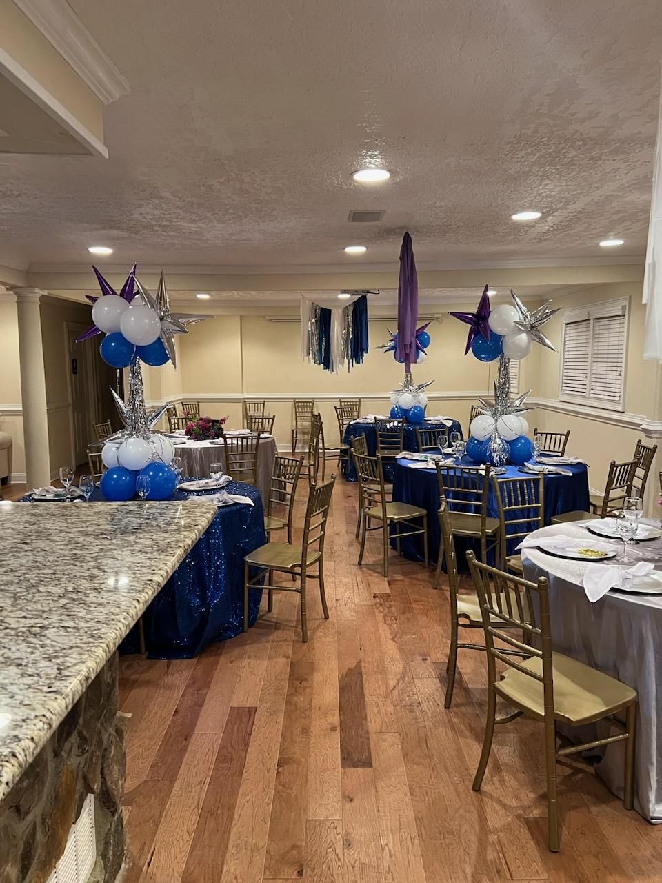 A large room filled with tables and chairs and balloons.
