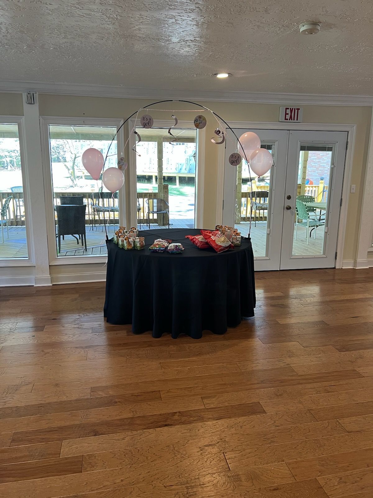 A table with a black tablecloth and balloons on it in a room.