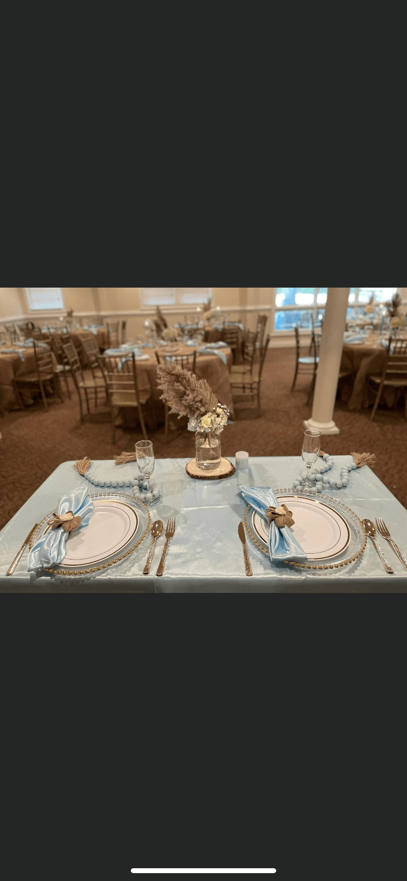 A table set for a wedding reception in a large room with tables and chairs.