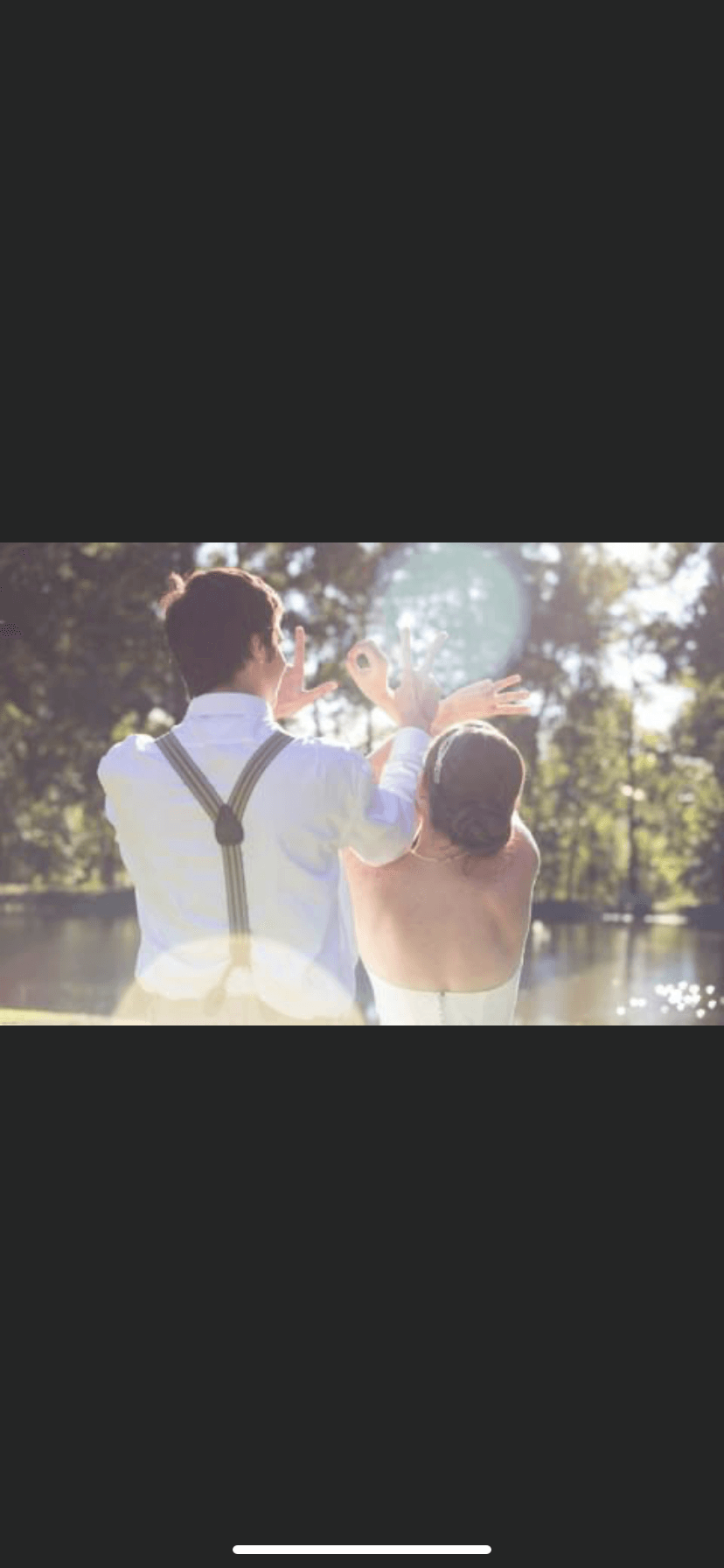 A bride and groom are standing next to each other in front of a lake.