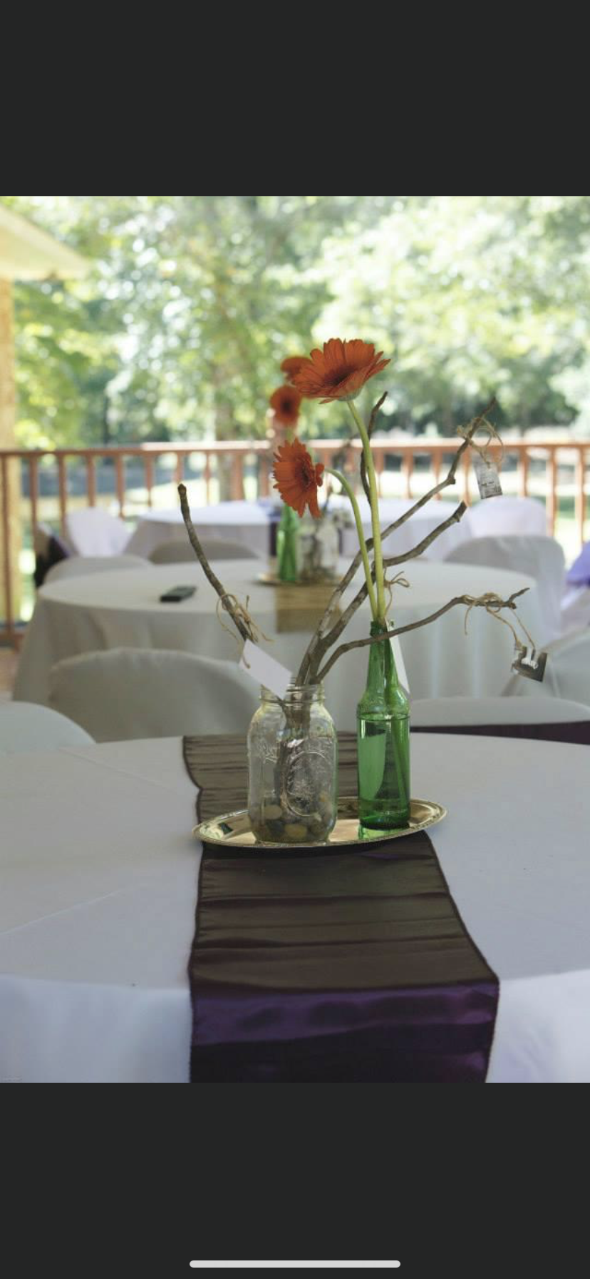 A table with a purple table runner and a vase of flowers on it.