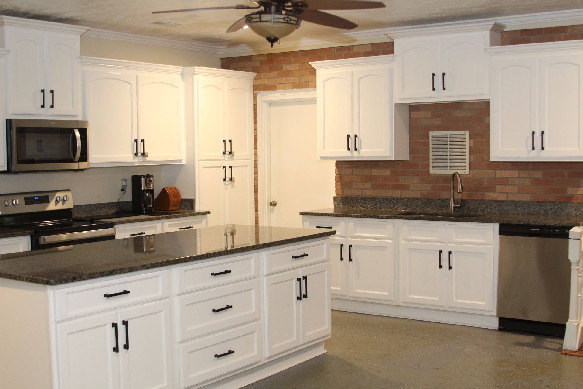 A kitchen with white cabinets and black counter tops