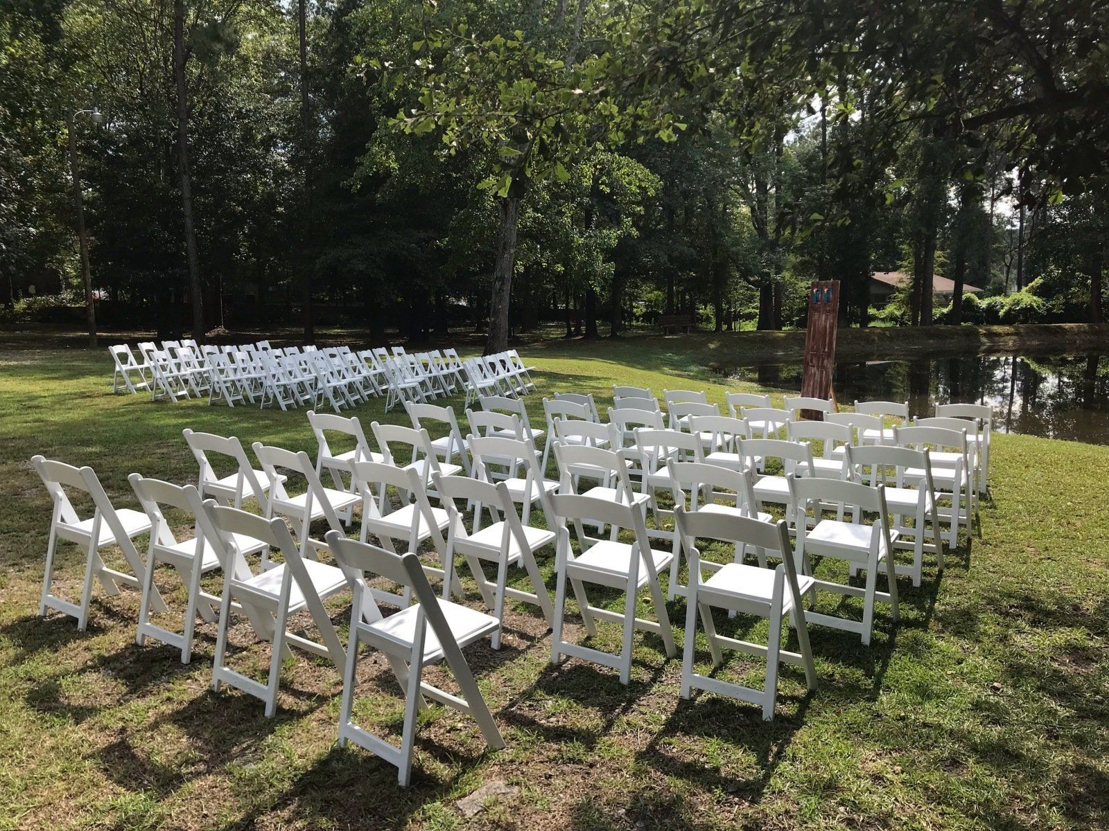 A row of white folding chairs sitting on top of a lush green field.