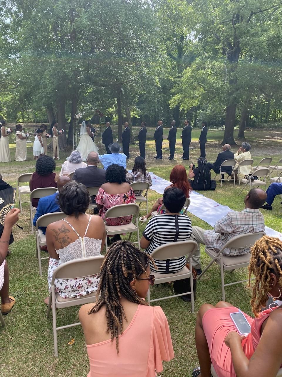 A group of people are sitting in folding chairs watching a wedding ceremony.