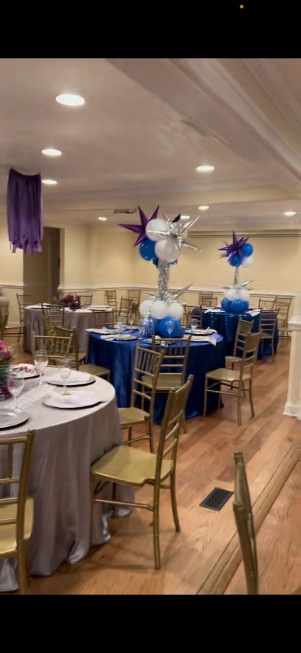 A large room with tables and chairs set up for a party.