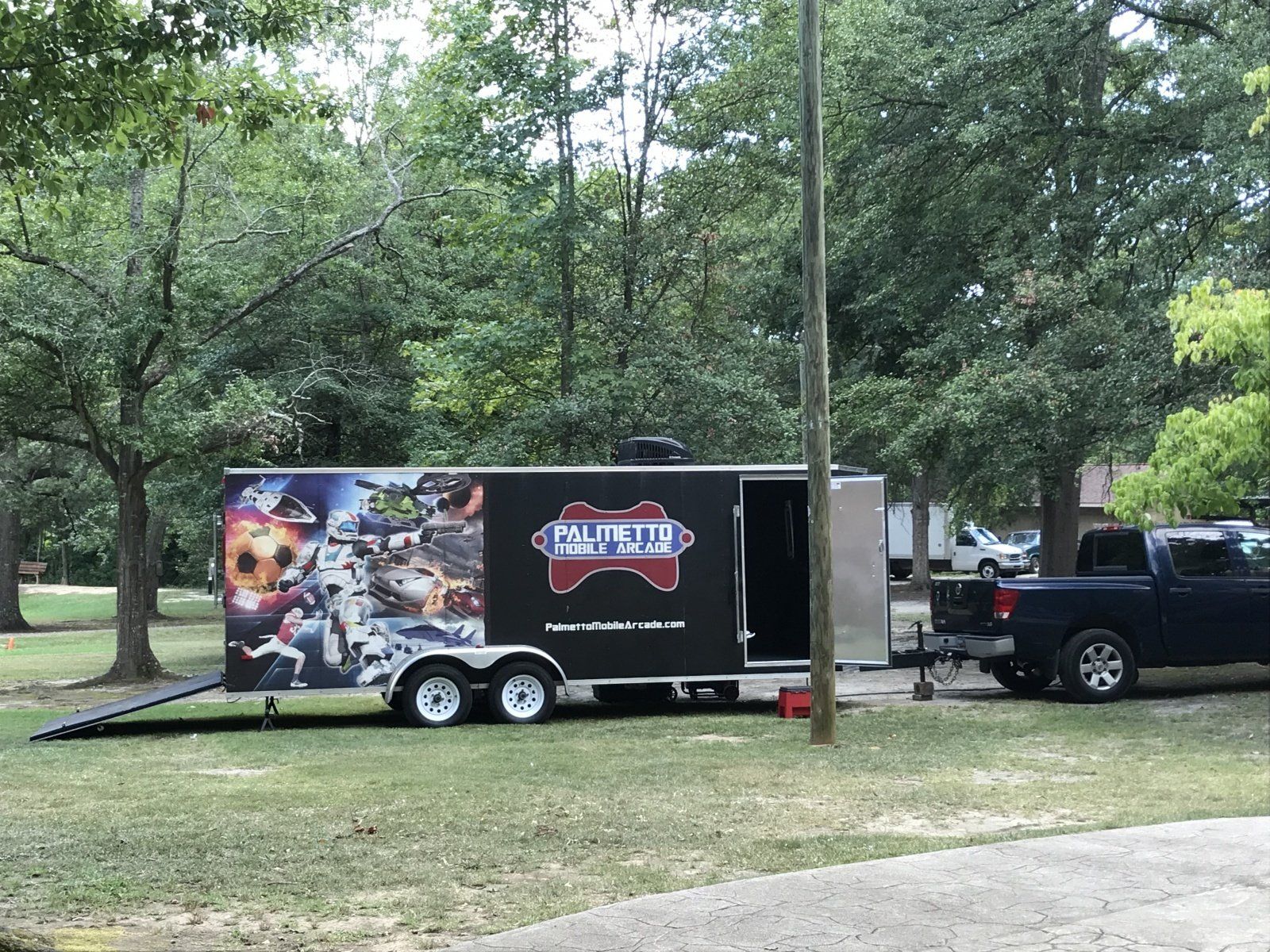 A trailer with a video game controller on it is parked next to a truck.