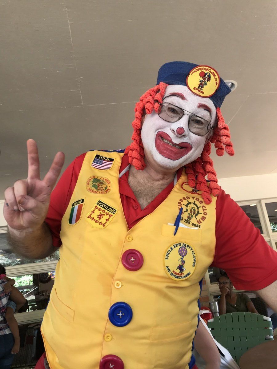 A man dressed as a clown is giving a peace sign