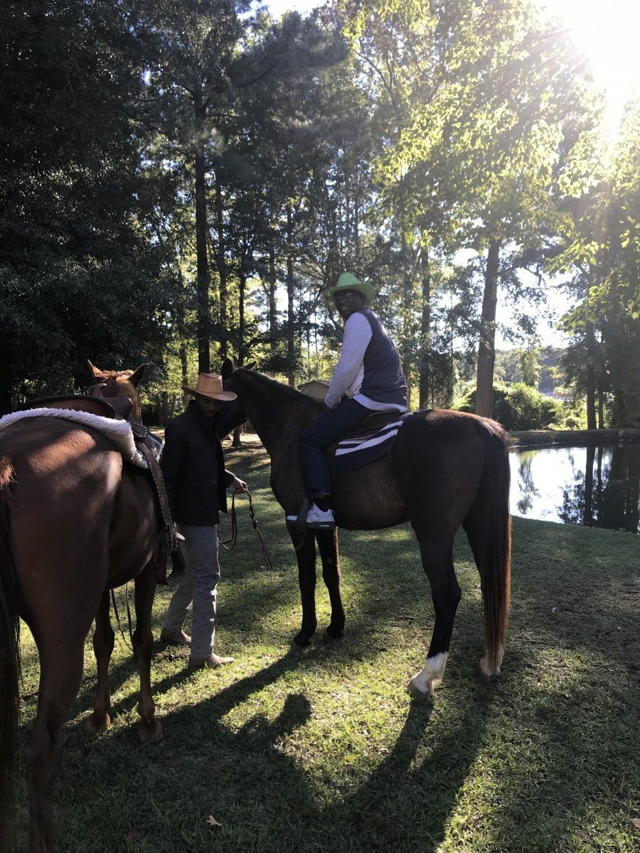 A man riding a horse in a field with trees in the background