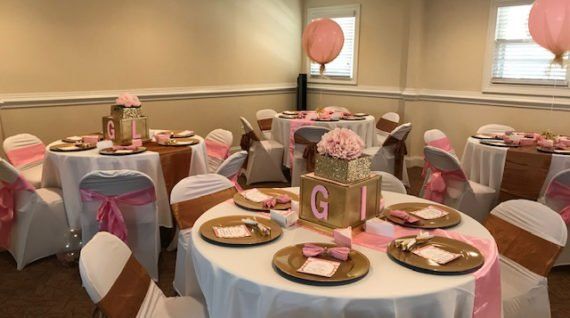 A room with tables and chairs set up for a baby shower.