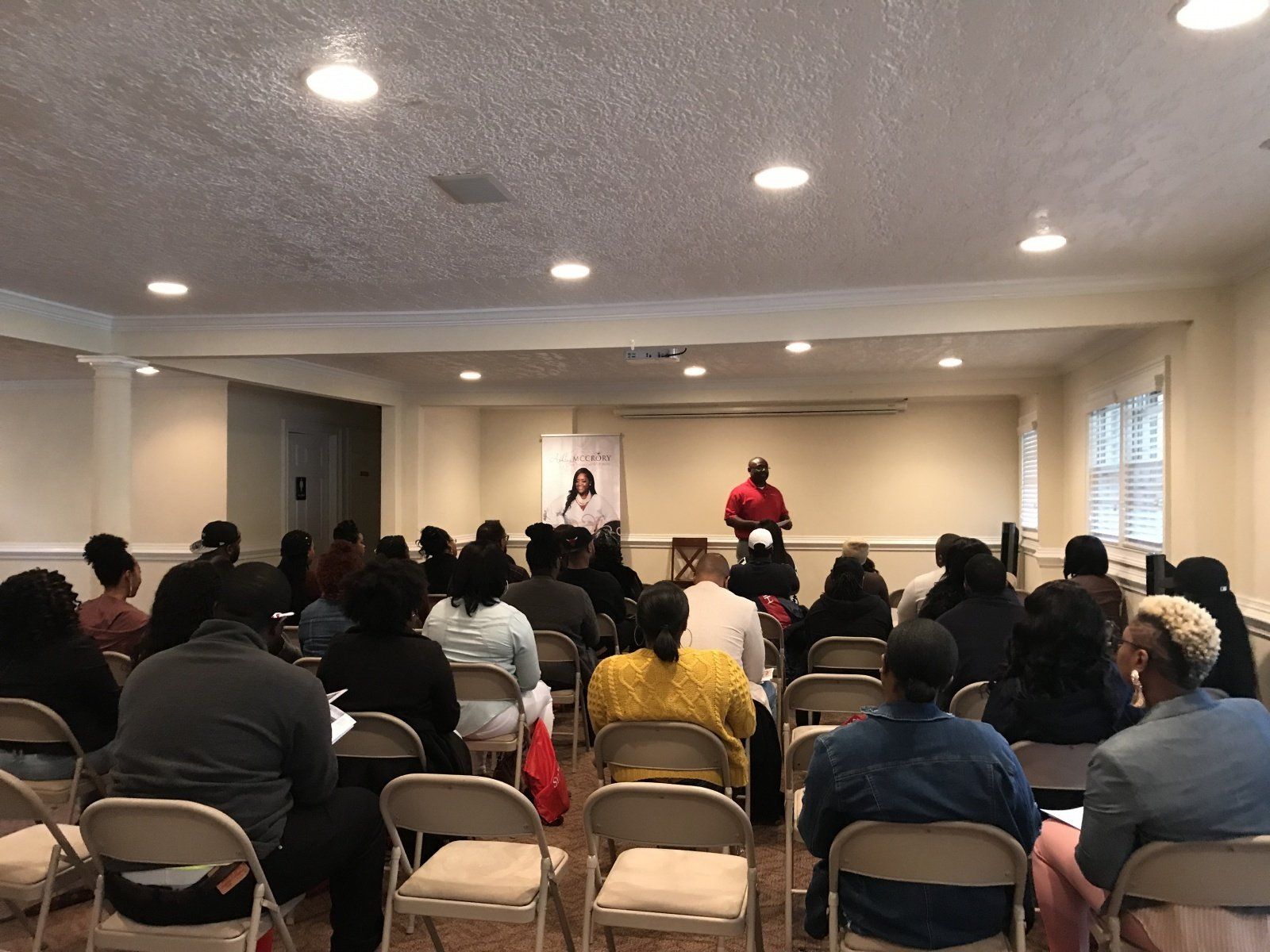 A group of people are sitting in folding chairs in a room.
