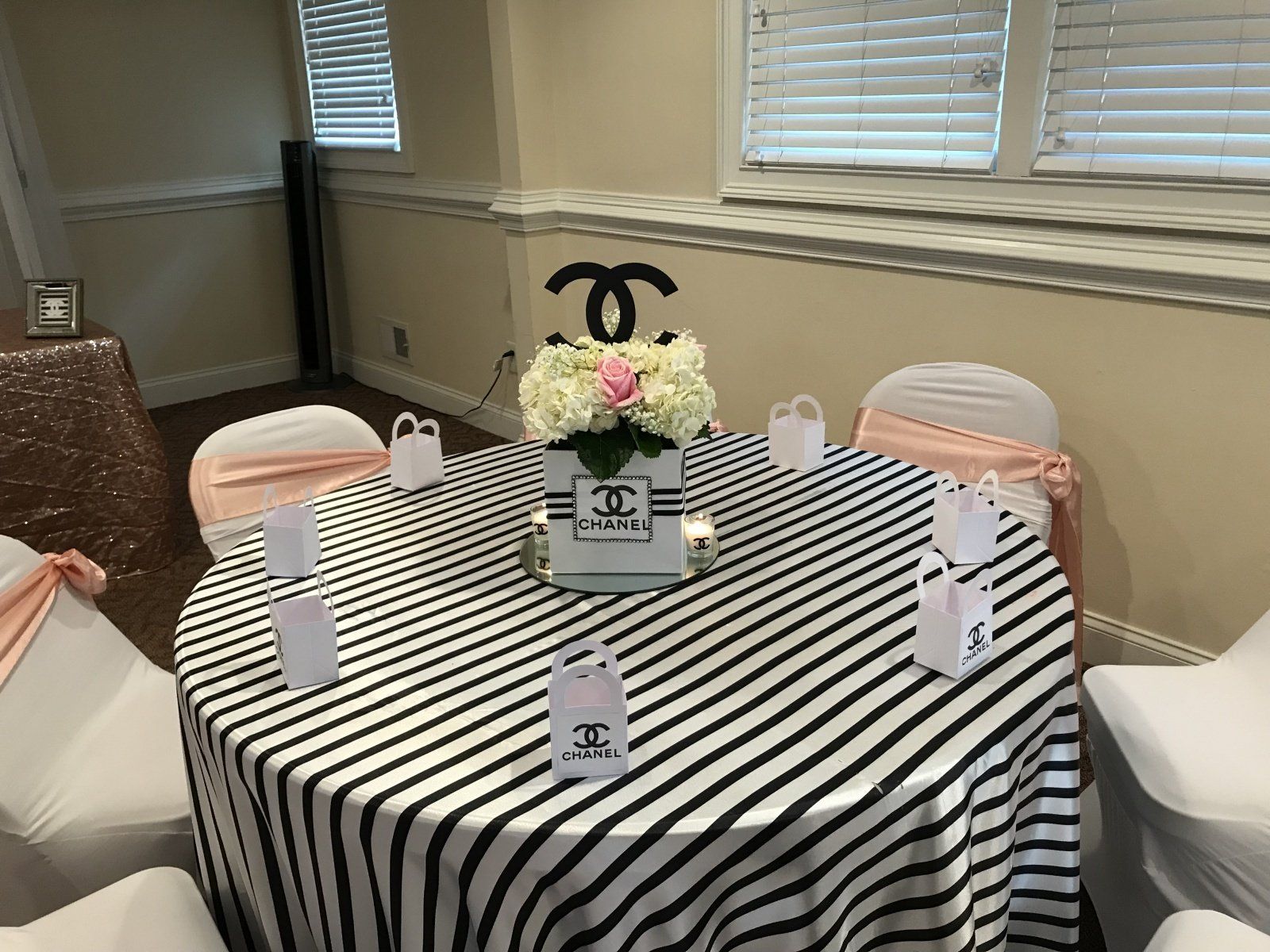 A table with a black and white striped tablecloth and a vase of flowers on it.