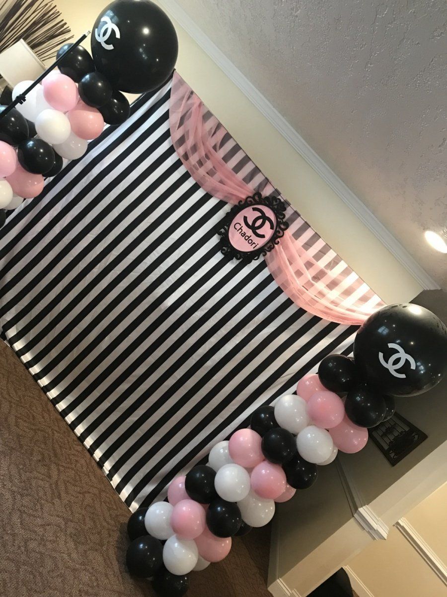 A black and white striped backdrop with pink and white balloons