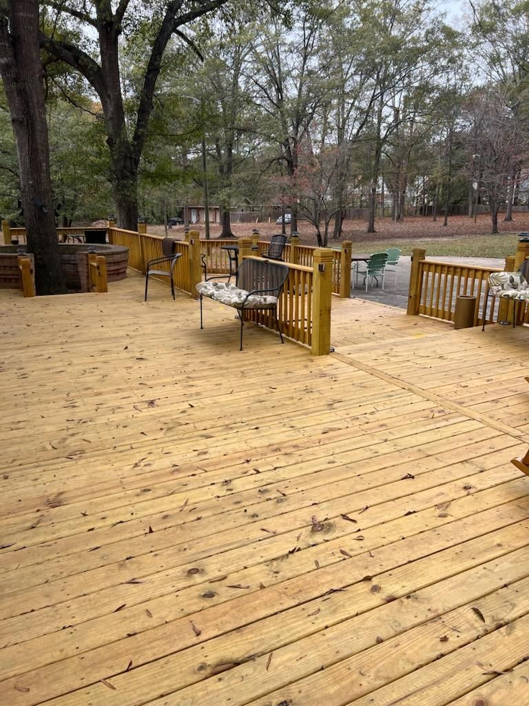 A wooden deck with a bench and chairs on it in a park.