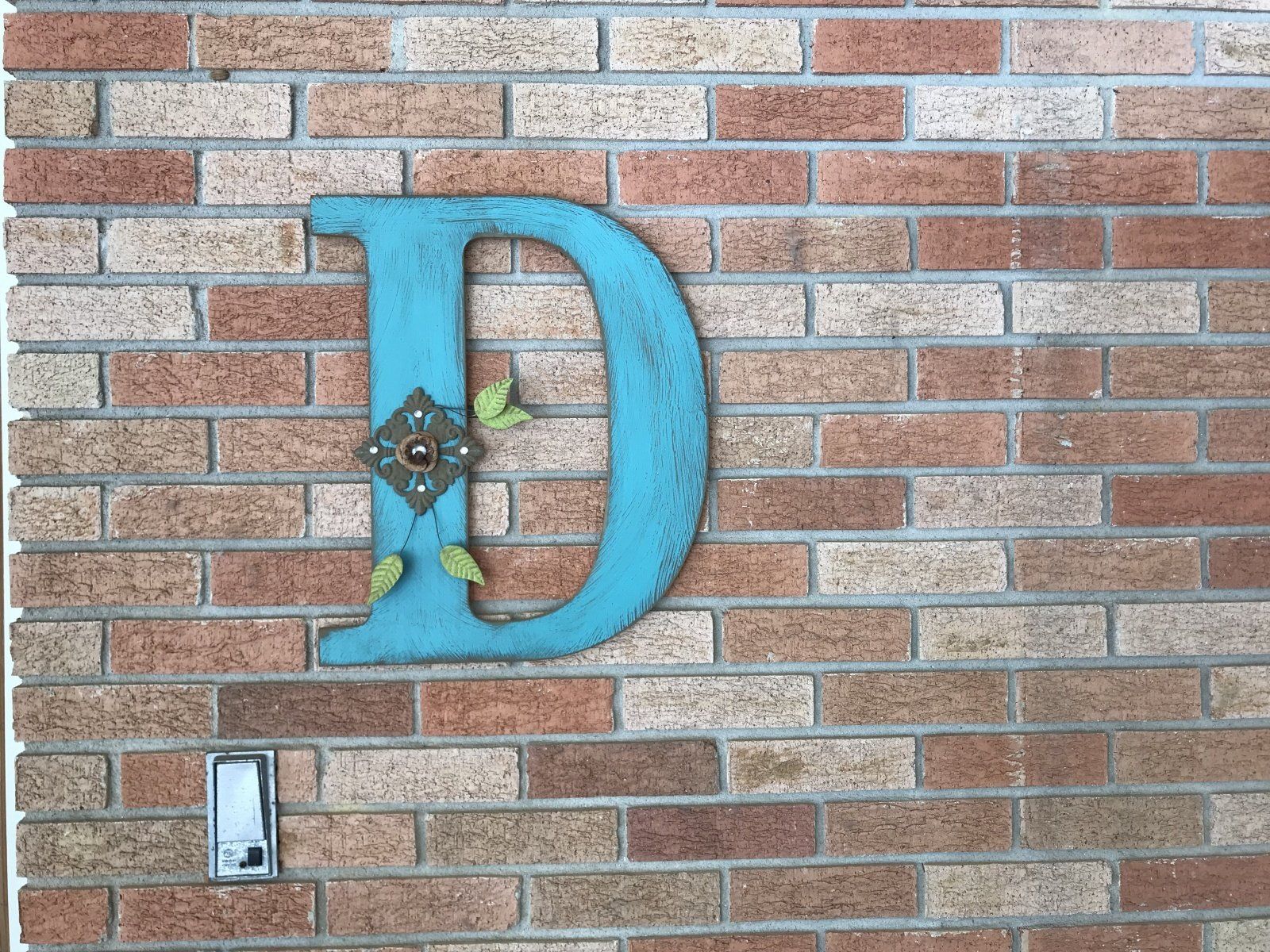 A blue letter d is hanging on a brick wall