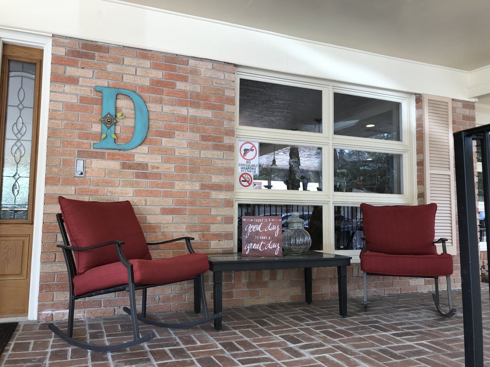 There are two rocking chairs and a table on the porch.