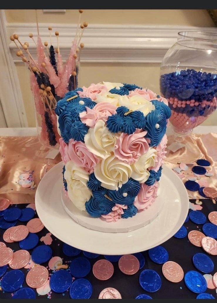 A cake with blue and pink frosting is sitting on a white plate on a table.
