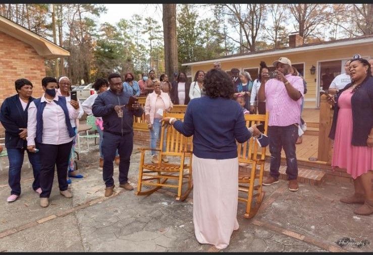 A group of people standing in front of rocking chairs