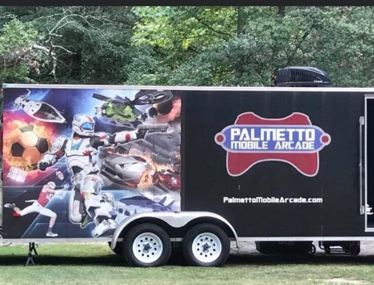 A palmetto mobile arcade trailer is parked in the grass