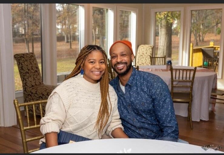 A man and a woman are posing for a picture while sitting at a table.