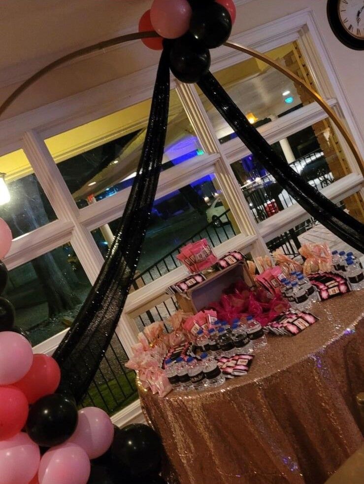 A table with balloons and cupcakes on it and a clock on the wall.