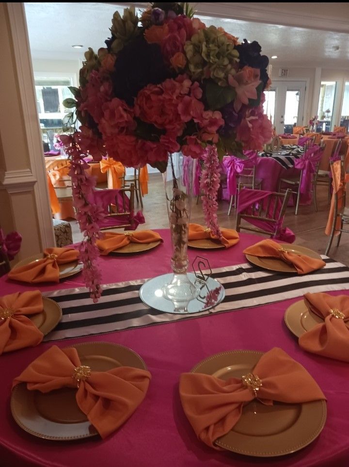A table with plates and napkins and a vase of flowers on it
