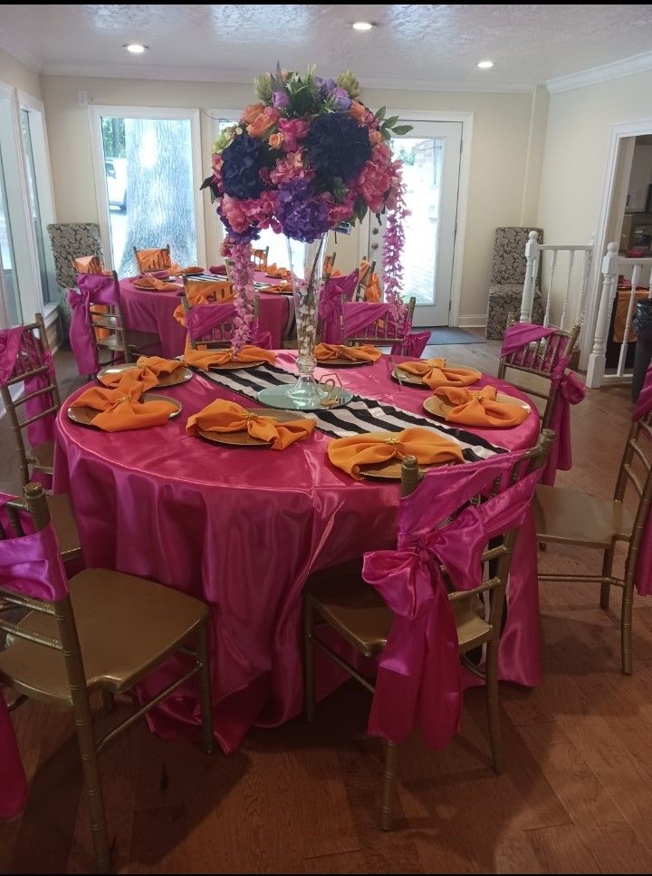 A table with a pink table cloth and a vase of flowers on it