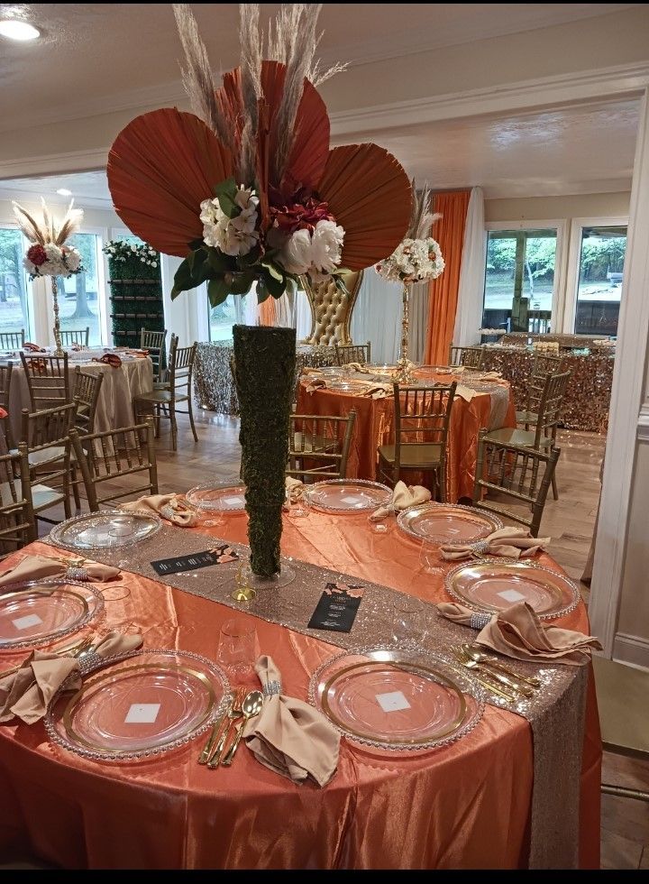 A table with plates , napkins , and a vase of flowers on it.