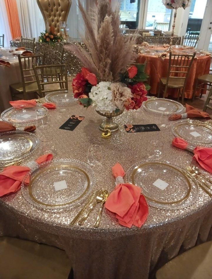 A table with plates , silverware , and a vase of flowers on it.