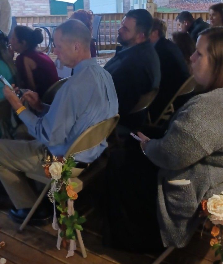 A group of people are sitting in chairs looking at their phones