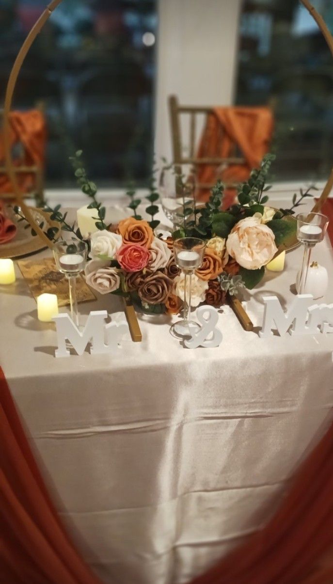 A table with flowers and candles on it and a window in the background.