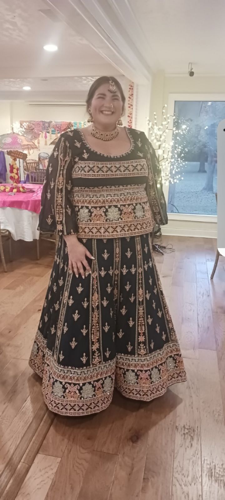 A woman in a black and gold dress is standing in a room.