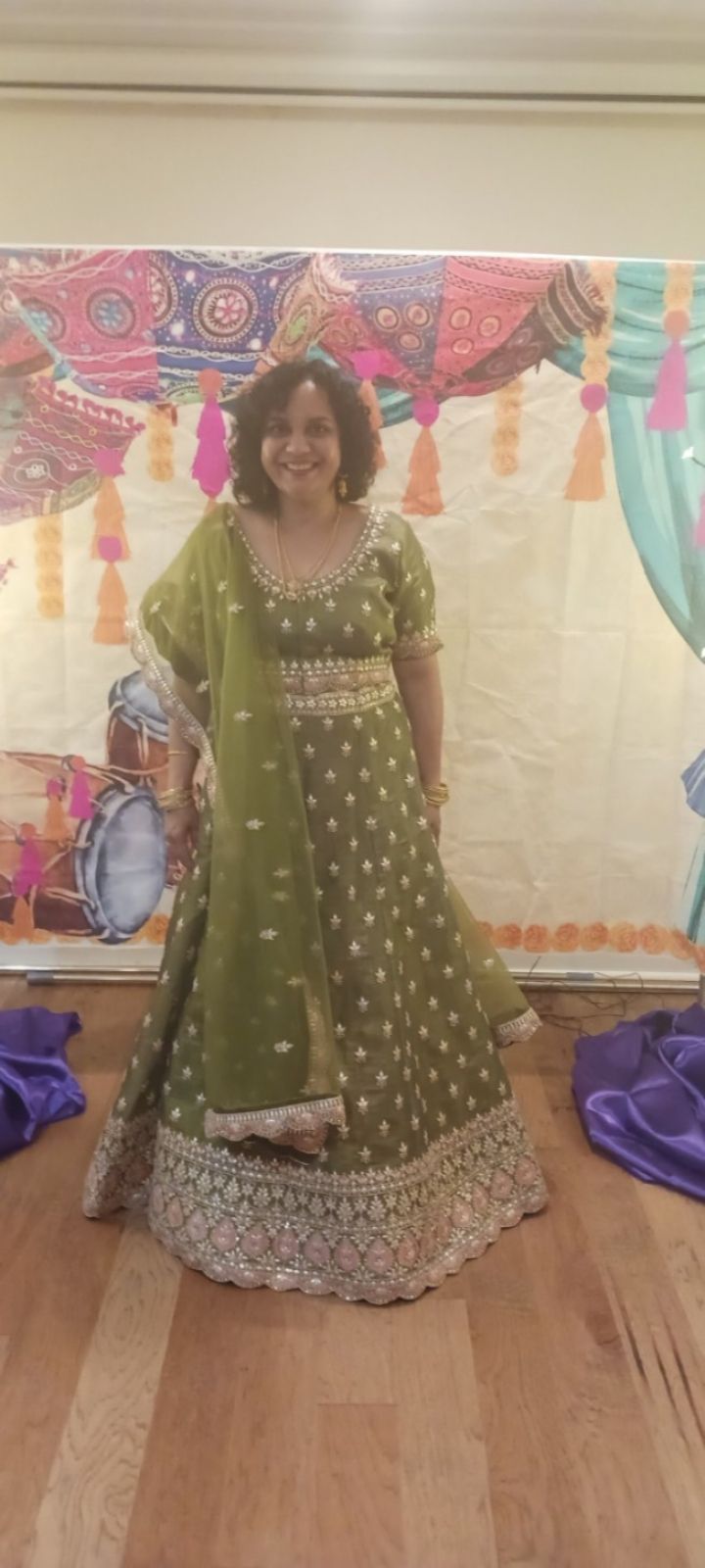 A woman in a green dress is standing in front of a wall.