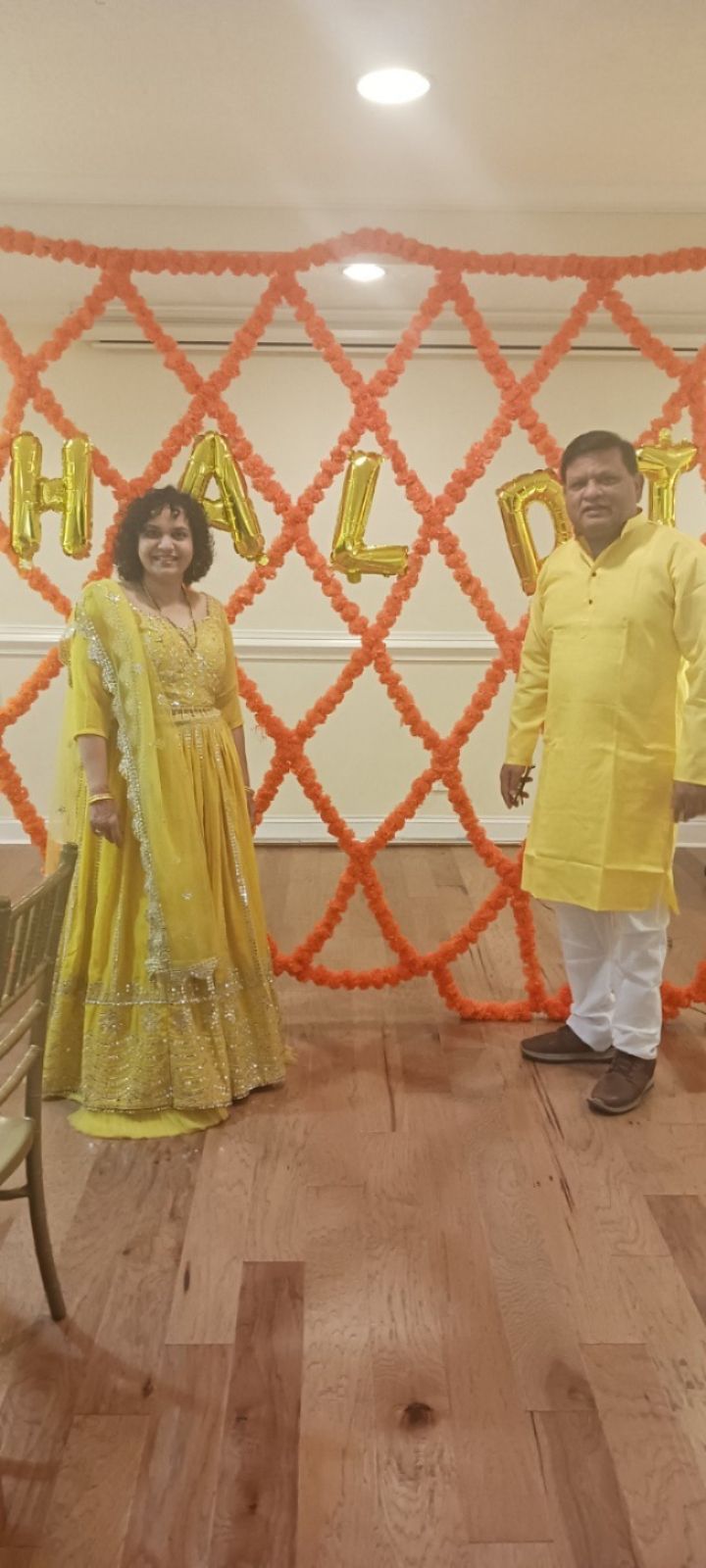 A man and a woman are standing in front of a wall decorated with balloons.