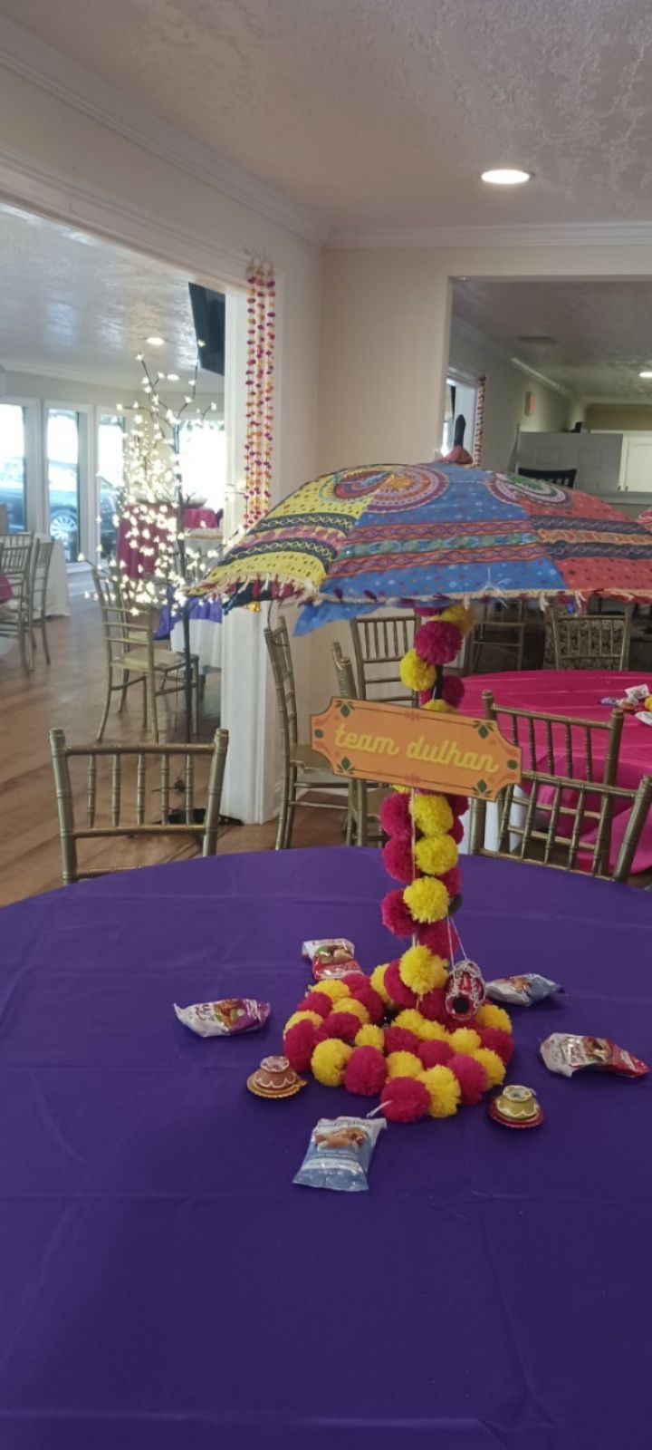 A table with a purple tablecloth and a colorful umbrella on it.