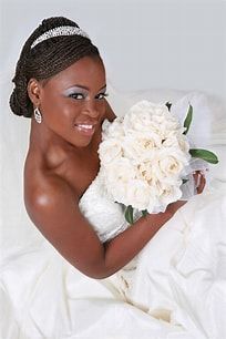 A bride in a white dress is holding a bouquet of white roses.
