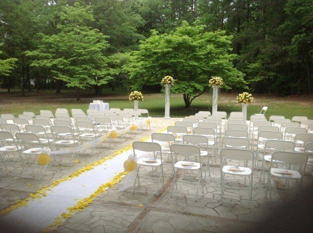 A row of white chairs are lined up for a wedding ceremony.