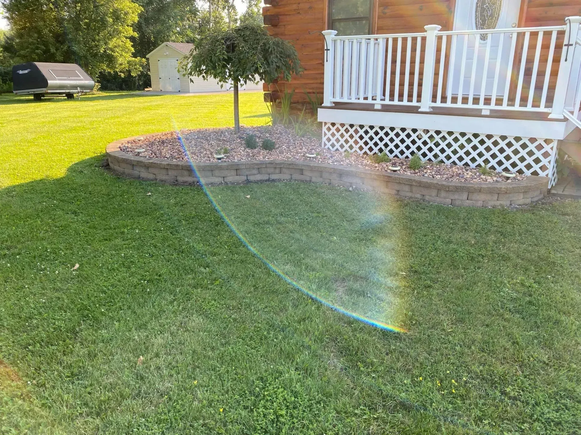 There is a rainbow in the grass in front of a house.